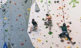 Three Young Men Are Climbing The Public Lands Climbing Wall