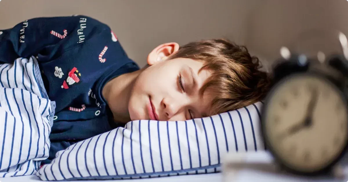 Little blond boy sleeping soundly lying on his side in bed